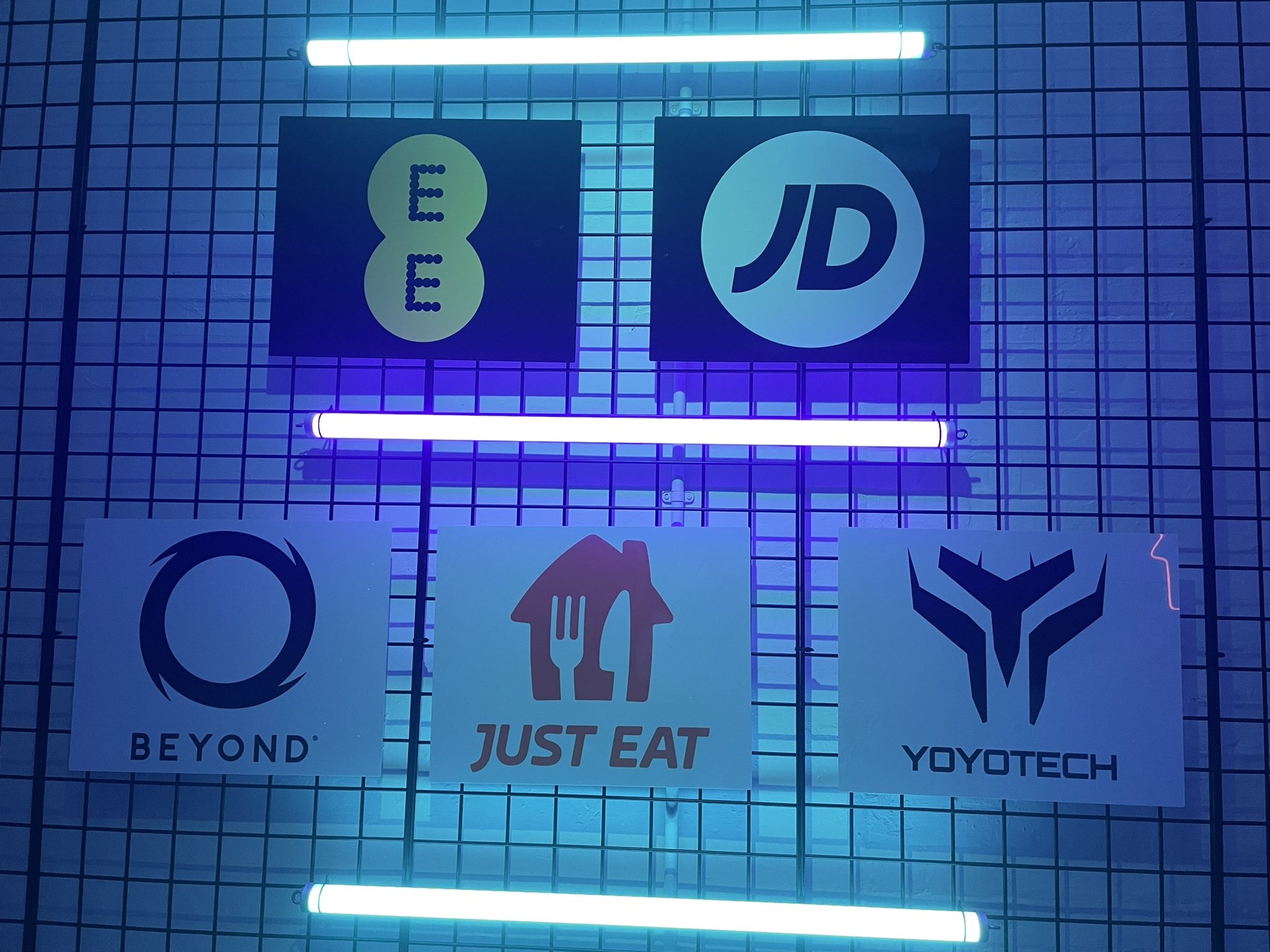XL LAUNCH 1 Company logos for sponsors of XL esports on metal grid with florescent tube lighting