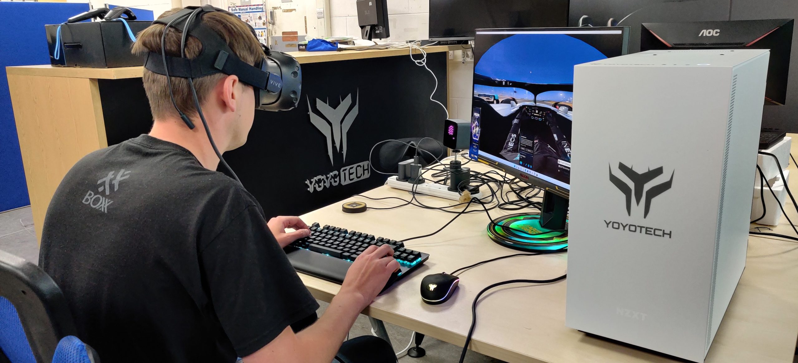 Young man wearing VR headset playing VR game on Yoyotech computer with keyboard