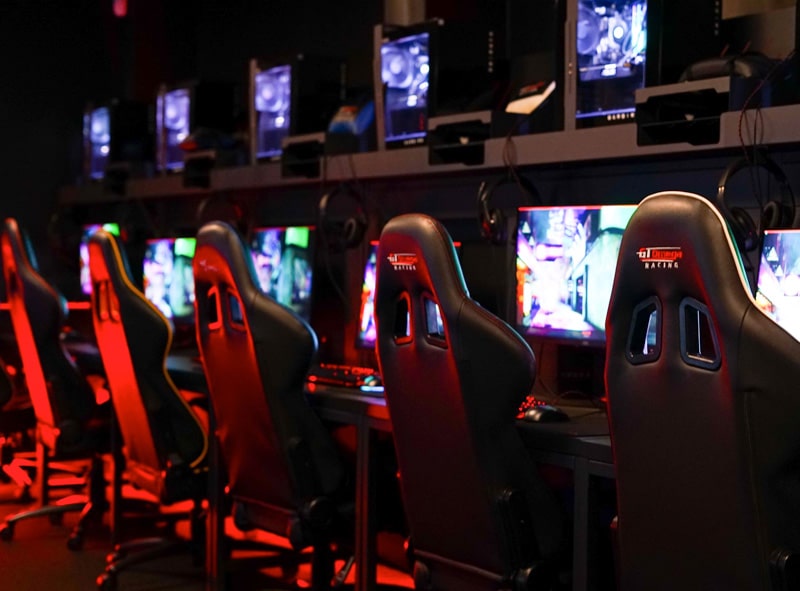 dark esports arena space, with gaming chairs and bright, colourful gaming screens